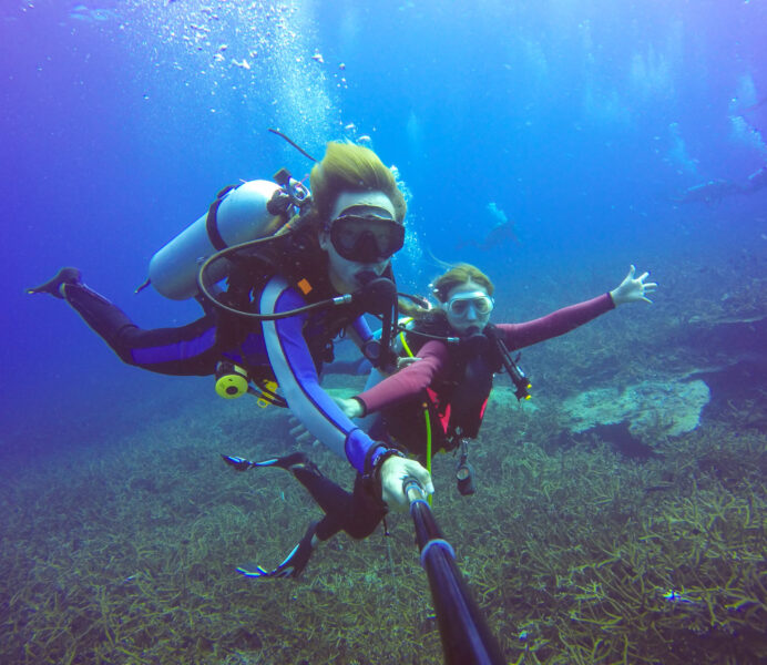 Underwater scuba diving selfie shot with selfie stick. Deep blue sea. Wide angle shot.